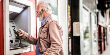 Senior man putting a Credit Card in ATM.