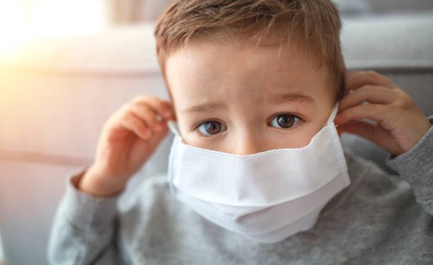 2-3 years old cute child wearing surgical mask. Little boy trying to stay healthy by wearing a mask to protect him against corona virus covid-19 / 2019-nCov. Little boy wearing anti virus mask staying at home