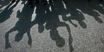 Protesters cast a shadow as they march on a street