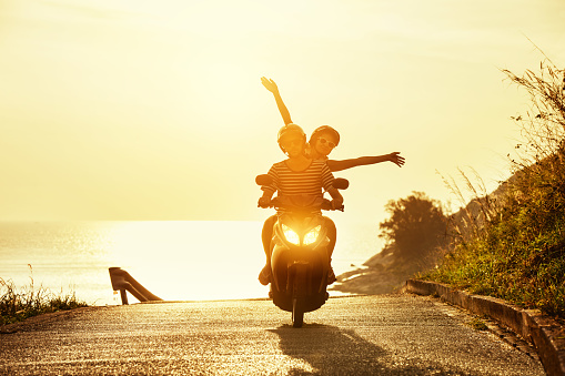 Happy couple traveling on motorcycle on sea coastal road. Travel concept