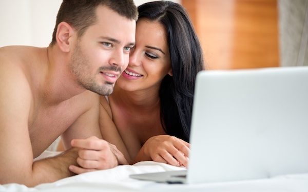 Couple watching porn movie over laptop in bedroom